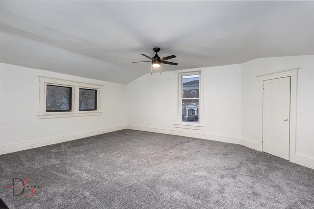 an empty room with windows and ceiling fan