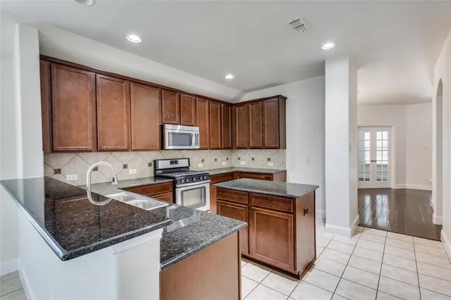 a kitchen with granite countertop stainless steel appliances a sink a counter top space cabinets and a window