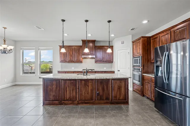 a kitchen with stainless steel appliances granite countertop a refrigerator a sink and a stove