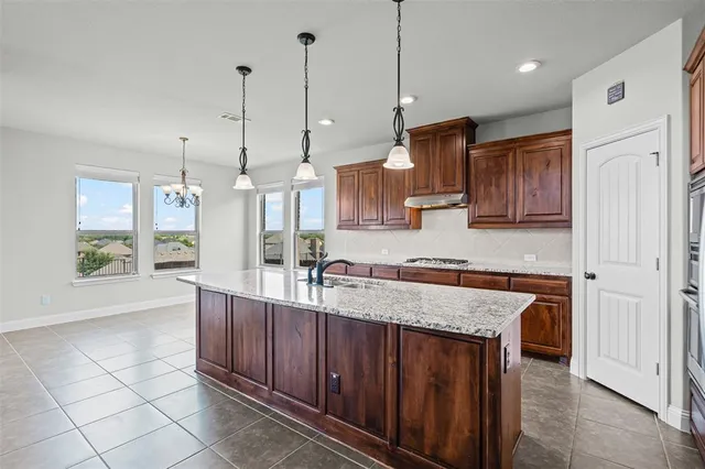 a large kitchen with granite countertop a stove a sink and a refrigerator