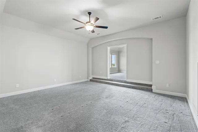 a view of an empty room with a chandelier fan