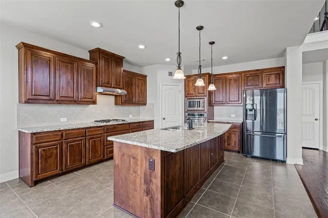a kitchen with stainless steel appliances granite countertop a refrigerator a sink and wooden cabinets