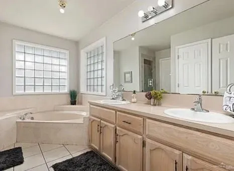 a bathroom with a double vanity sink a mirror and a bathtub