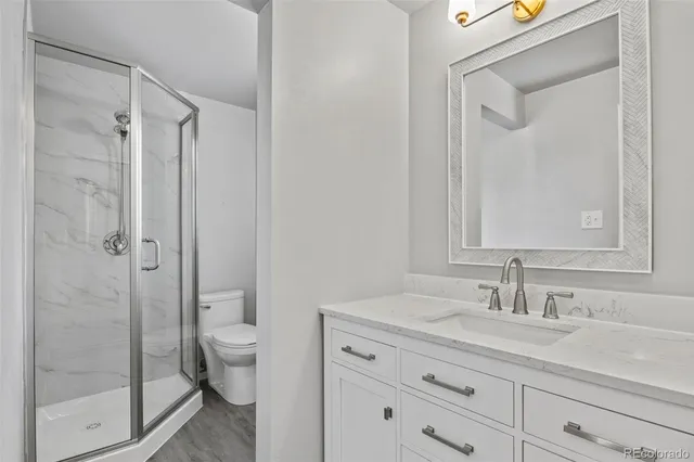 a bathroom with a granite countertop sink a toilet and shower