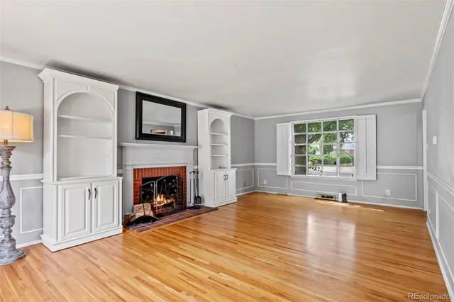 a view of a livingroom with wooden floor a fireplace and windows