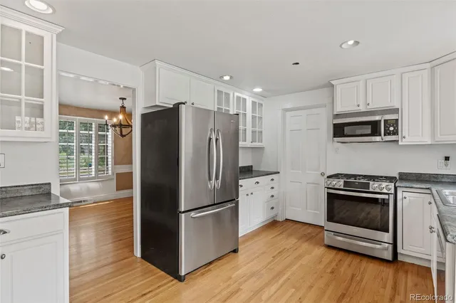 a kitchen with granite countertop a refrigerator stove and wooden floor