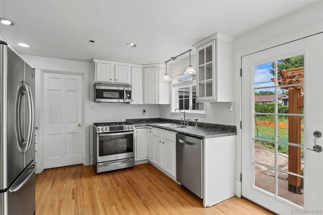 a kitchen with stainless steel appliances granite countertop a stove top oven a sink and a refrigerator