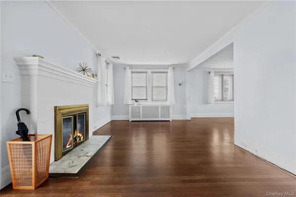 a view of an empty room with wooden floor fireplace and a window