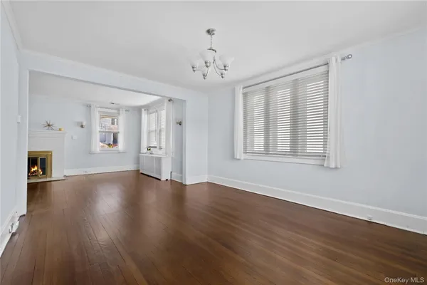 a view of an empty room with window and wooden floor