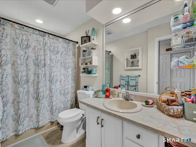 a bathroom with a granite countertop sink a toilet and a shower