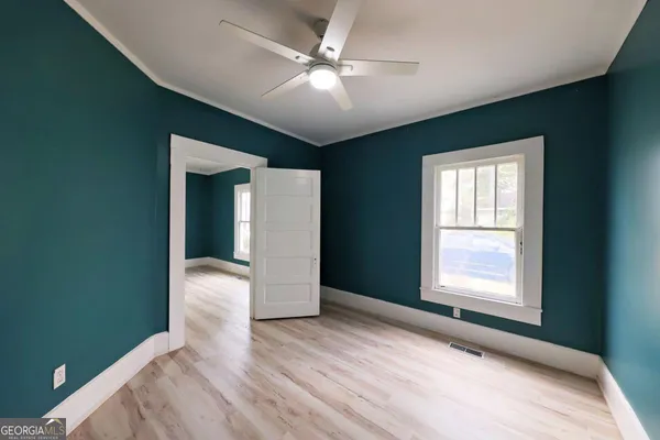 a view of an empty room with window and wooden floor