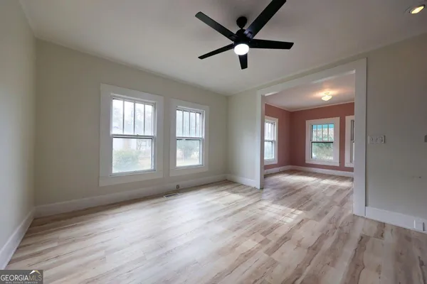 a view of empty room with wooden floor and fan