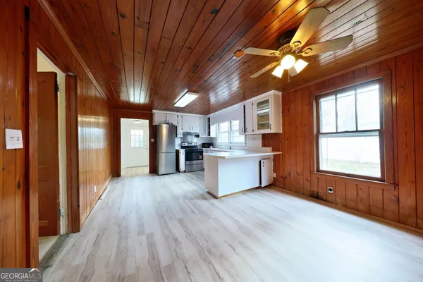 a kitchen with stainless steel appliances kitchen island granite countertop a refrigerator a sink dishwasher a stove and a dining table with wooden floor