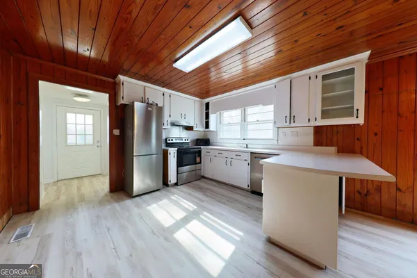 a kitchen with stainless steel appliances granite countertop a refrigerator a sink dishwasher a stove with wooden floors and cabinets