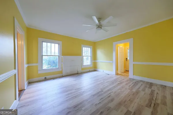 a view of an empty room with window and wooden floor