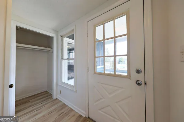 a view of an empty room with wooden floor and a window