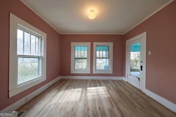 a view of an empty room with wooden floor and a window