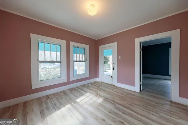 an empty room with wooden floor and windows