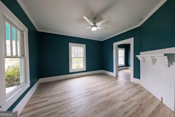 a view of an empty room with a window and wooden floor