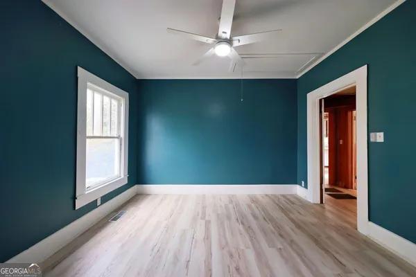 an empty room with wooden floor chandelier fan and windows