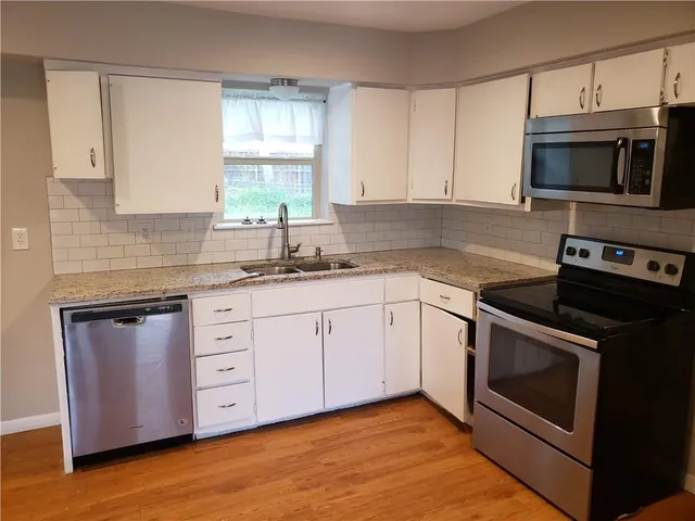a kitchen with granite countertop white cabinets stainless steel appliances and a sink