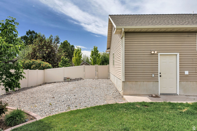 2912 South 1080th Street West Logan, UT 84321 - Photo 36 of 43 Rear exterior of the property featuring horizontal tan siding, a light-colored entry door, and two exterior light fixtures