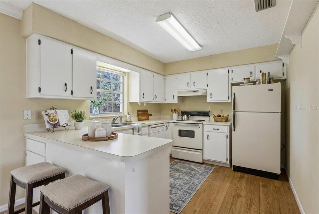 141 Northeast 50th Court Ocala, FL 34470 - Photo 13 of 42 a kitchen with a refrigerator a stove a sink dishwasher and white cabinets with wooden floor