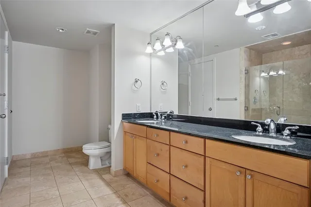 a bathroom with a granite countertop sink a toilet and a mirror