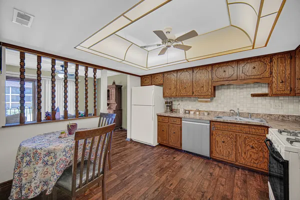 a kitchen with granite countertop wooden floors white cabinets and stainless steel appliances
