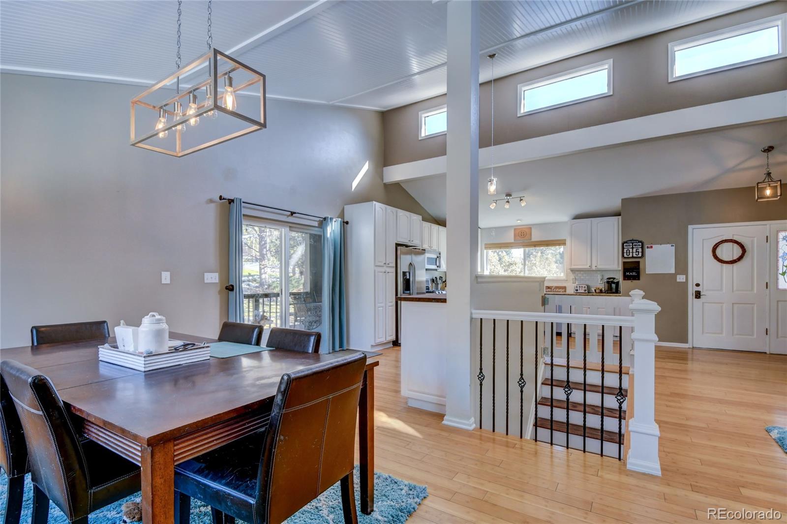 6359 Powell Road Parker, CO 80134 - Photo 13 of 38 a dining room with wooden floor a chandelier a wooden table and chairs