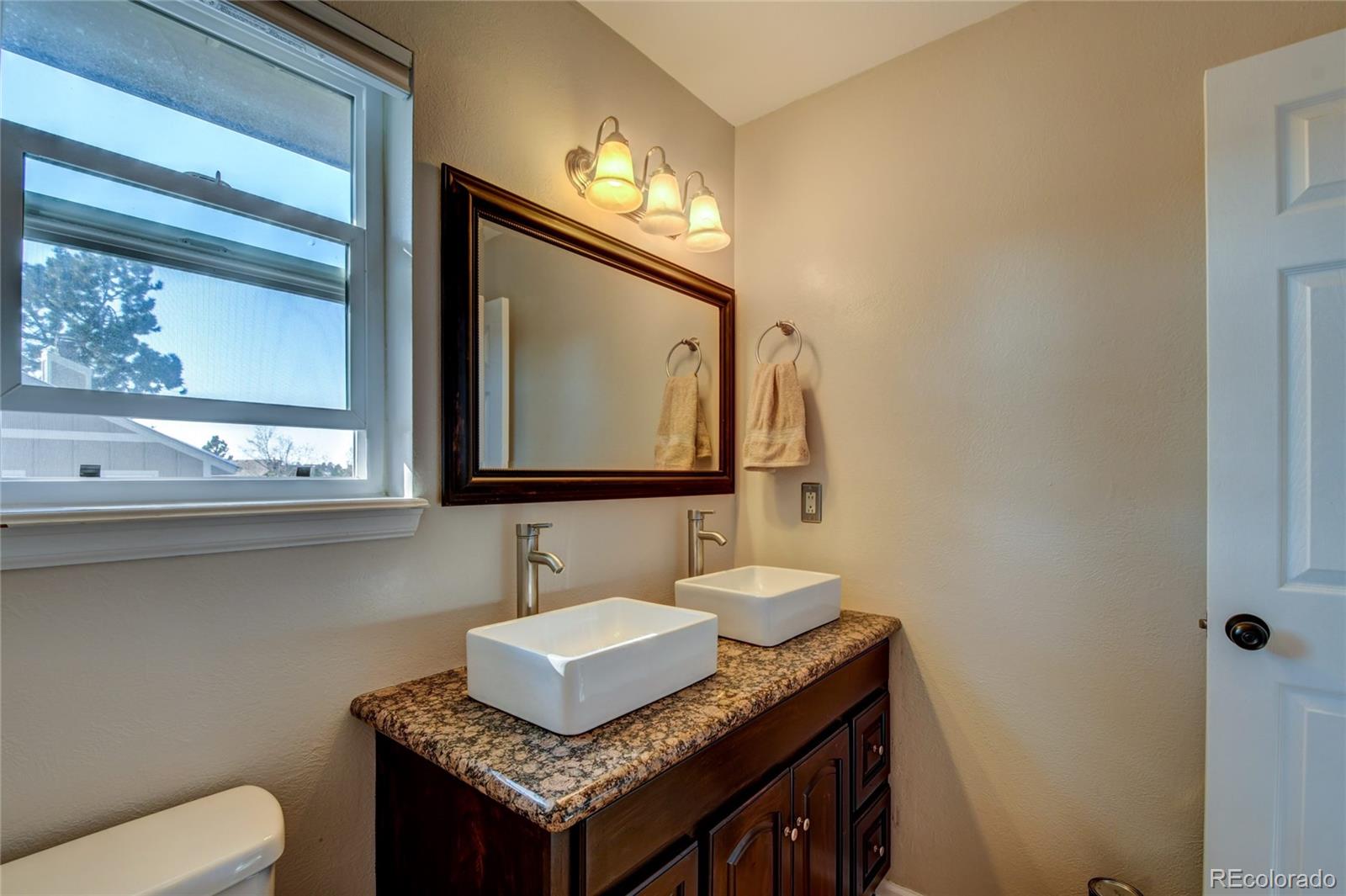 6359 Powell Road Parker, CO 80134 - Photo 22 of 38 a bathroom with a granite countertop sink and a mirror