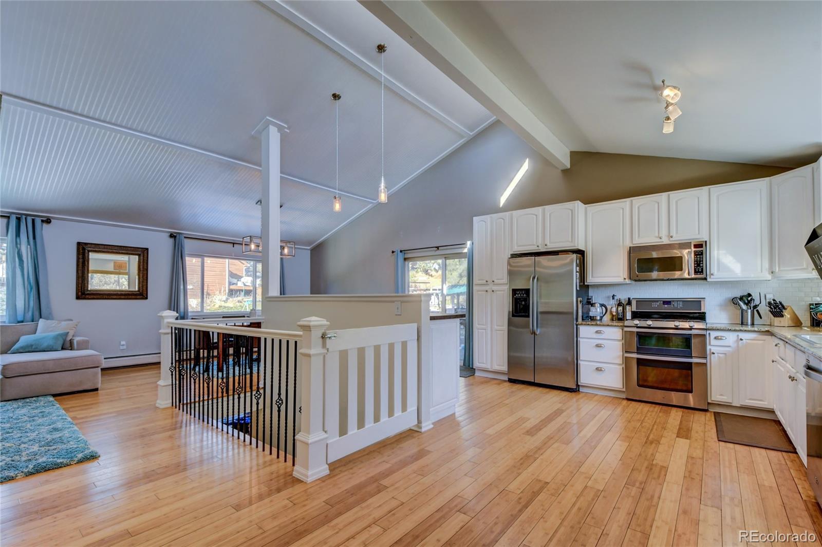 6359 Powell Road Parker, CO 80134 - Photo 4 of 38 a kitchen with stainless steel appliances granite countertop a refrigerator oven a stove top oven a sink dishwasher a dining table and chairs with wooden floor
