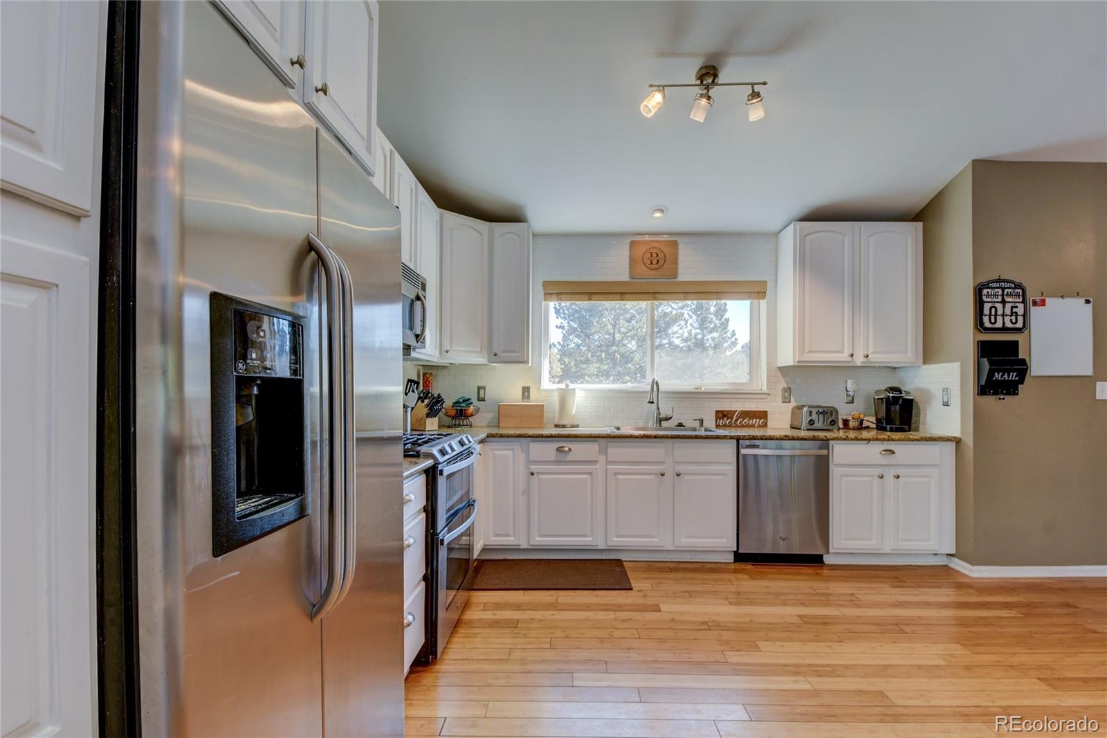 6359 Powell Road Parker, CO 80134 - Photo 7 of 38 a kitchen with granite countertop a refrigerator and a stove top oven