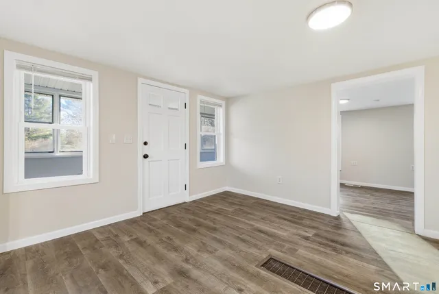 a view of empty room with wooden floor and fan
