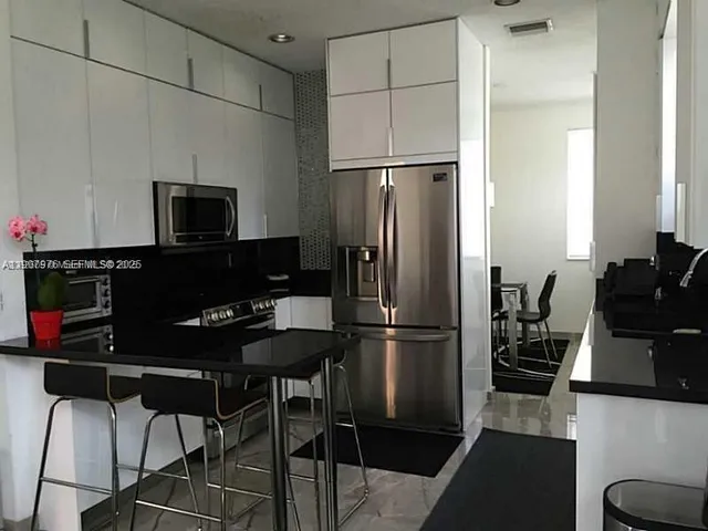 a kitchen with a refrigerator and a stove top open