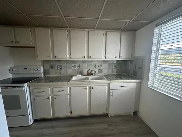 a kitchen with stainless steel appliances granite countertop a sink a stove a microwave oven and white cabinets