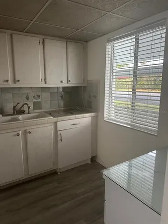 a kitchen with white cabinets and wooden floor