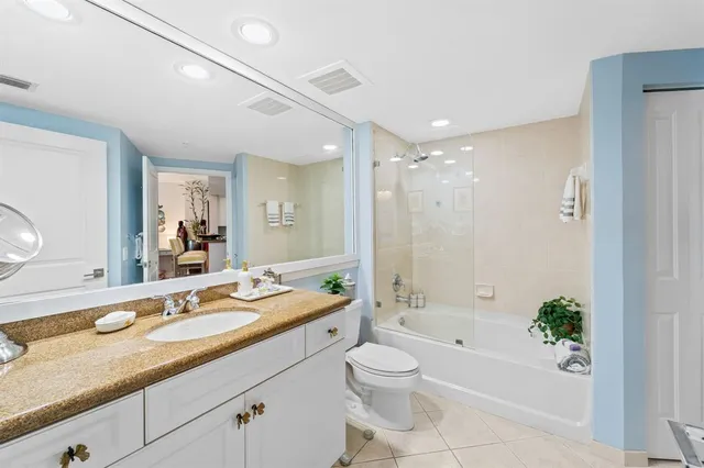 a bathroom with a granite countertop sink a toilet a bathtub and shower