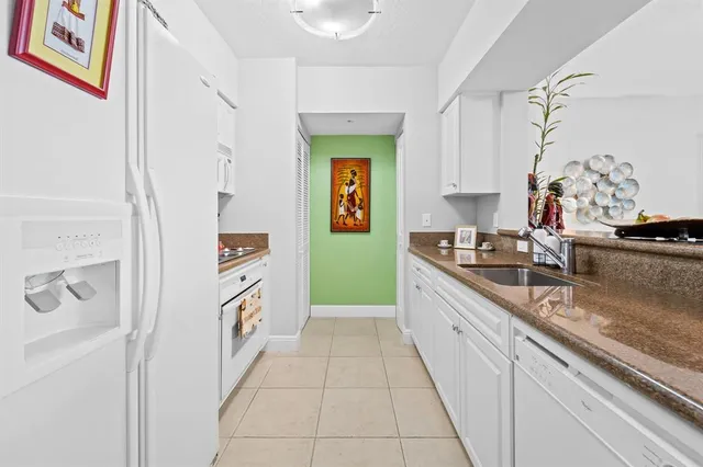 a large white kitchen with a sink and dishwasher a refrigerator with wooden floor