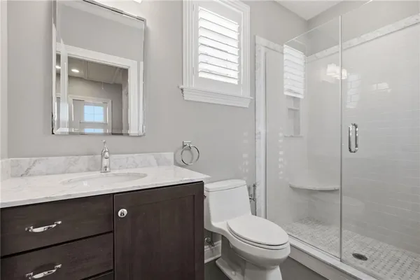 a bathroom with a toilet a sink a mirror and shower