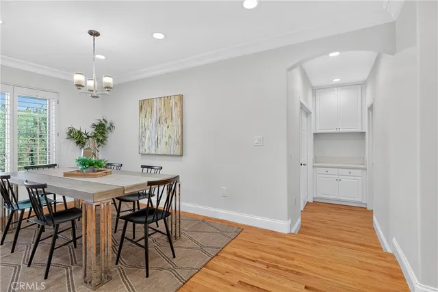 a dining room with wooden floor a chandelier a wooden table and chairs