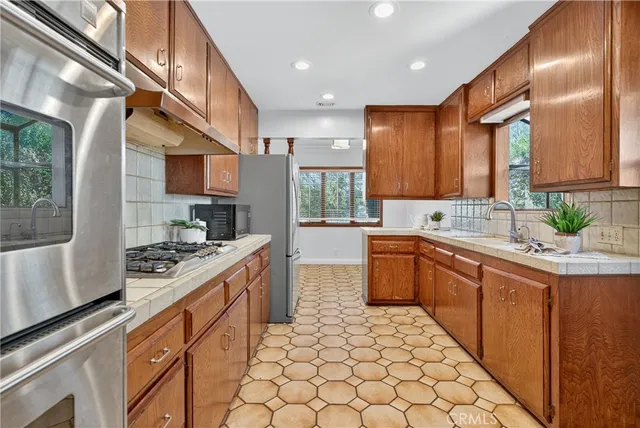 a kitchen with stainless steel appliances granite countertop a stove a sink and a refrigerator