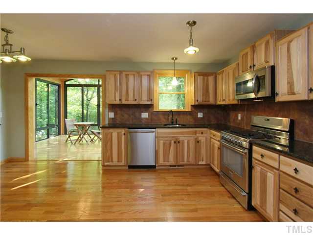 6248 Rushingbrook Drive Raleigh, NC 27612 - Photo 3 of 25 a kitchen with stainless steel appliances granite countertop a sink a stove top oven a chimney cabinets and a dining table