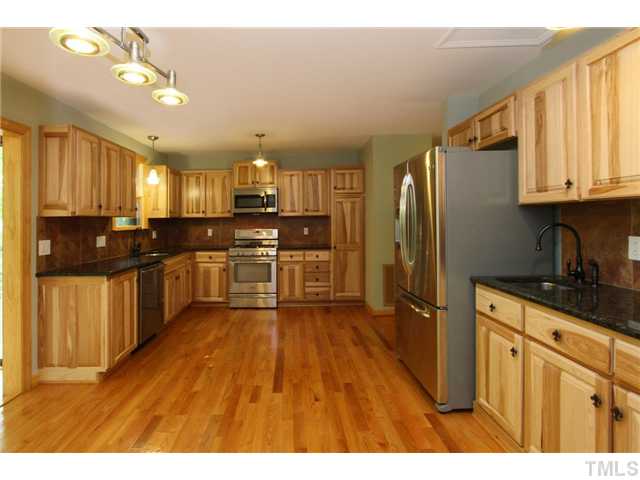6248 Rushingbrook Drive Raleigh, NC 27612 - Photo 4 of 25 a kitchen with stainless steel appliances granite countertop a refrigerator a sink dishwasher a stove with wooden cabinets and floor