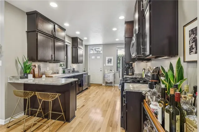a kitchen with stainless steel appliances kitchen island granite countertop a table chairs in it and wooden floors