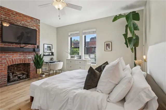 a bedroom with a bed a flat screen tv and a fireplace