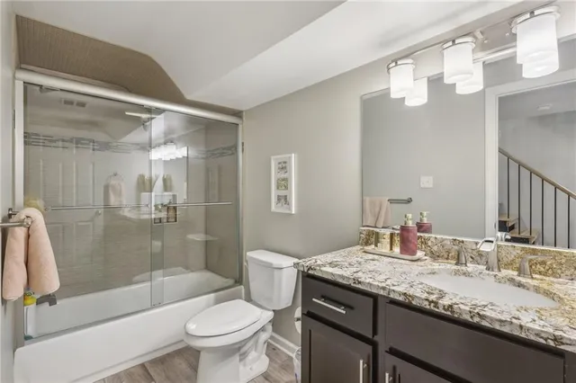 a bathroom with a granite countertop sink a toilet a mirror and shower