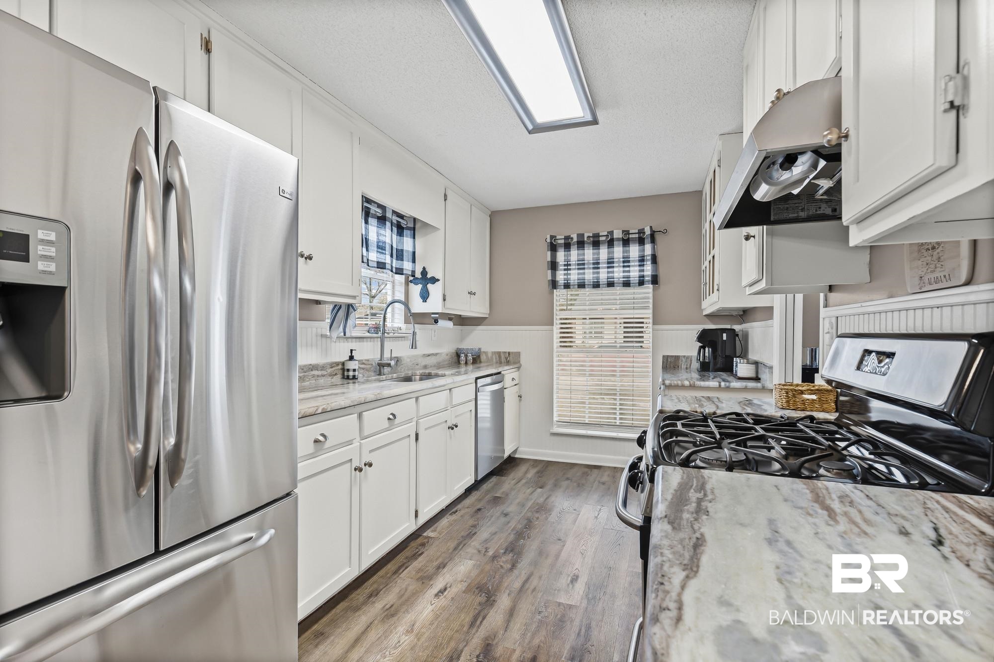 6609 Blakeley Court Mobile, AL 36695 - Photo 6 of 28 Kitchen featuring stainless steel appliances, white cabinets, light stone counters, dark wood-type flooring, and a textured ceiling