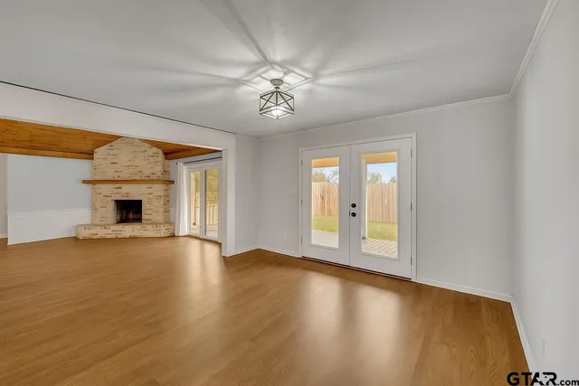 an empty room with wooden floor fireplace and windows