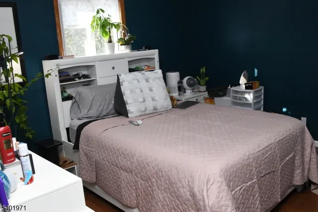 a bedroom with a bed a potted plant on the dresser and a potted plant